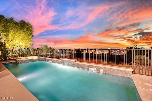 pool at dusk with pool water feature and an in ground hot tub