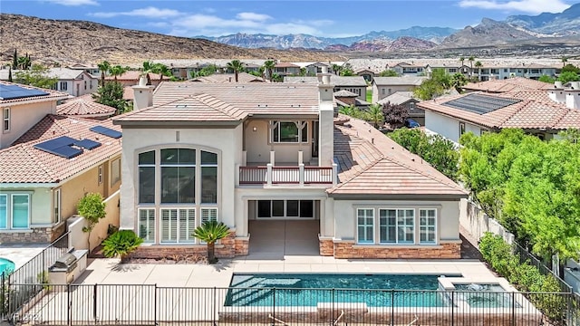 rear view of property with a fenced in pool, a mountain view, and a balcony