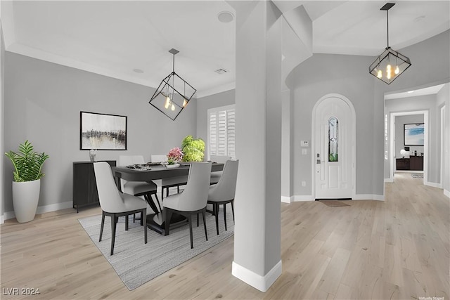 dining area with light hardwood / wood-style floors, an inviting chandelier, and crown molding