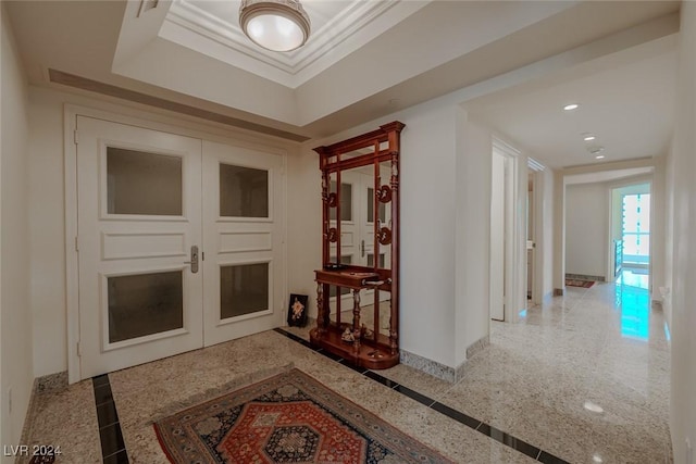 corridor featuring a raised ceiling and ornamental molding