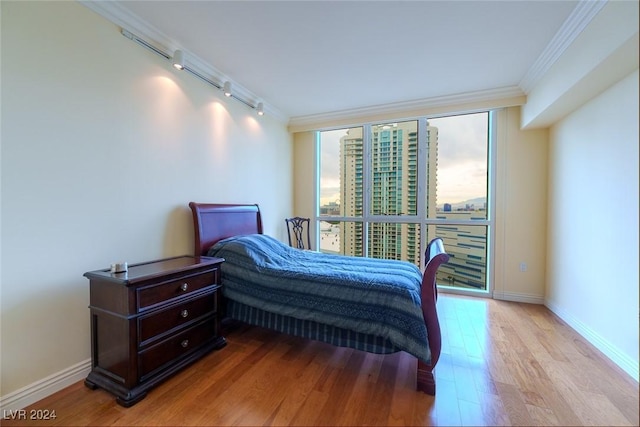 bedroom featuring floor to ceiling windows, crown molding, rail lighting, and light hardwood / wood-style flooring