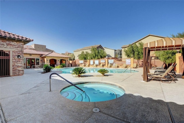 view of swimming pool featuring a community hot tub and a patio