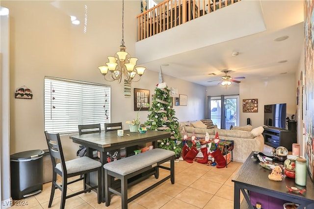 tiled dining area featuring a towering ceiling and ceiling fan with notable chandelier