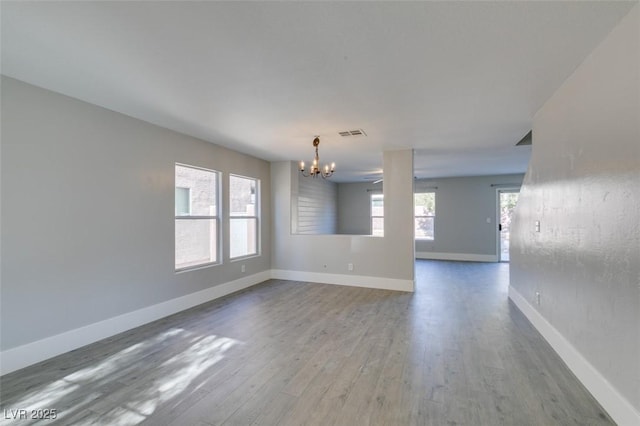 empty room featuring wood-type flooring and a notable chandelier