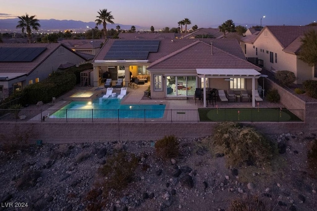 pool at dusk featuring a pergola and a patio area