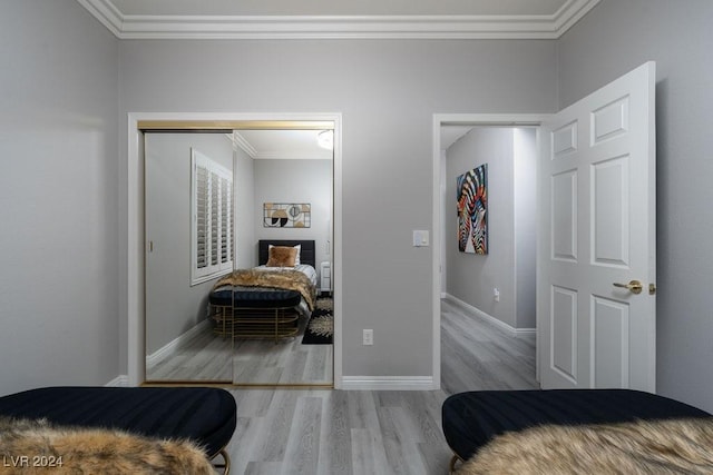 bedroom with ornamental molding, light hardwood / wood-style floors, and a closet