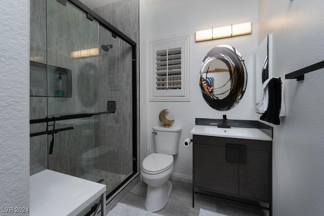 bathroom with vanity, a shower with door, and toilet