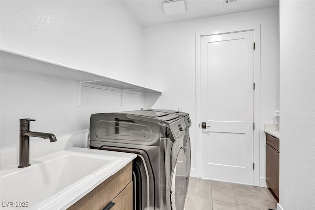 laundry room with cabinets, washing machine and clothes dryer, light tile patterned flooring, and sink