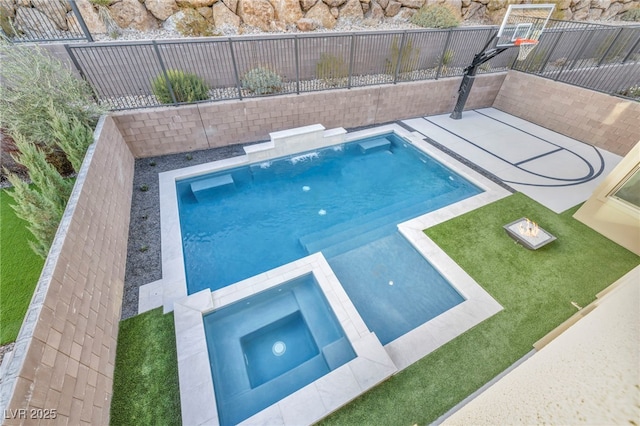 view of swimming pool with an in ground hot tub, basketball hoop, and a lawn