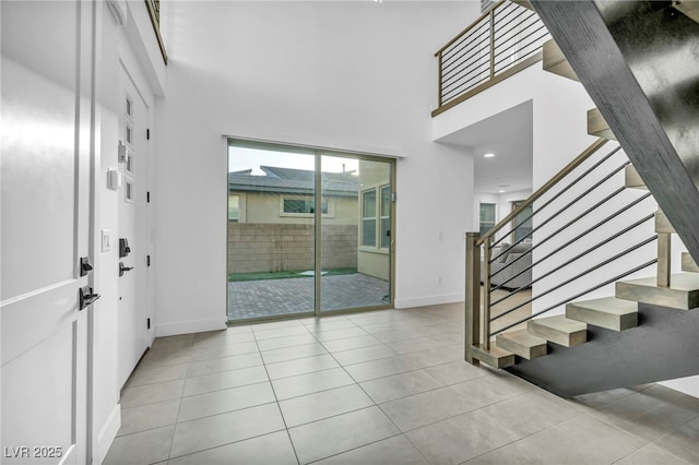 entryway with a towering ceiling and light tile patterned floors