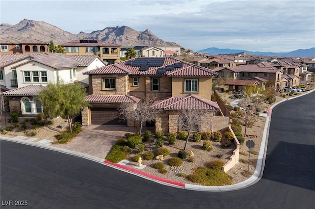 mediterranean / spanish-style home with stone siding, a residential view, a mountain view, and solar panels