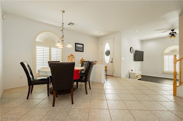 dining area featuring light tile patterned flooring and ceiling fan with notable chandelier