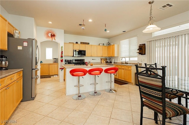 kitchen featuring sink, a center island, pendant lighting, a breakfast bar, and appliances with stainless steel finishes