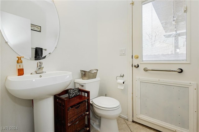 bathroom with tile patterned flooring, a healthy amount of sunlight, and toilet