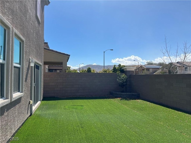 view of yard with a fenced backyard and a mountain view