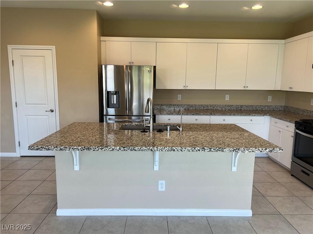 kitchen with stainless steel appliances, dark stone counters, a sink, and light tile patterned floors