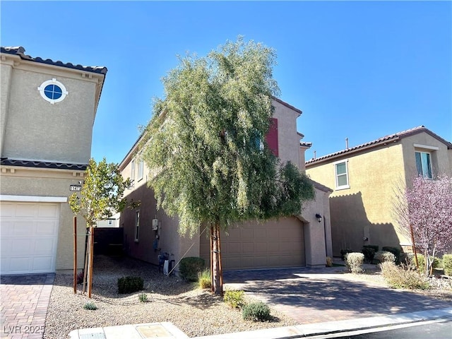 mediterranean / spanish house with an attached garage, decorative driveway, and stucco siding