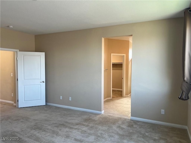 unfurnished bedroom featuring carpet floors, a spacious closet, and baseboards