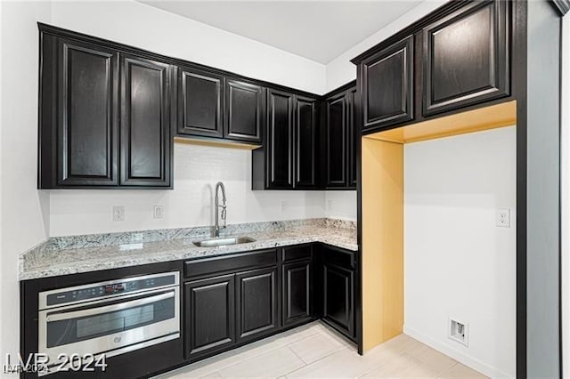 kitchen featuring oven, light stone counters, and sink