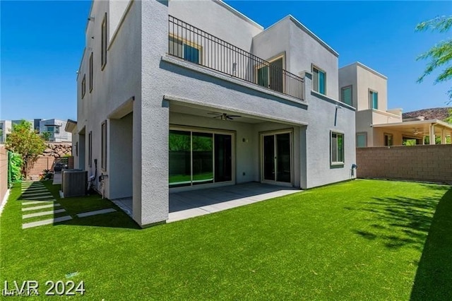 rear view of property with a lawn, ceiling fan, a balcony, central AC unit, and a patio area