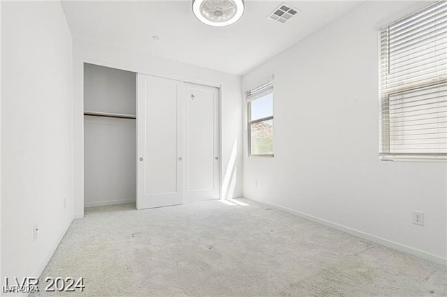 unfurnished bedroom featuring light carpet and a closet