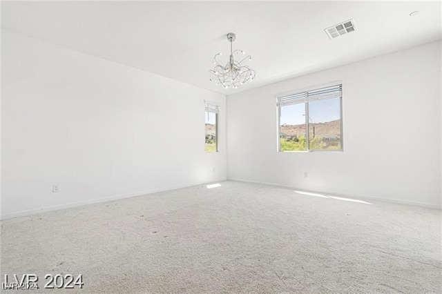 unfurnished room with carpet flooring and a notable chandelier