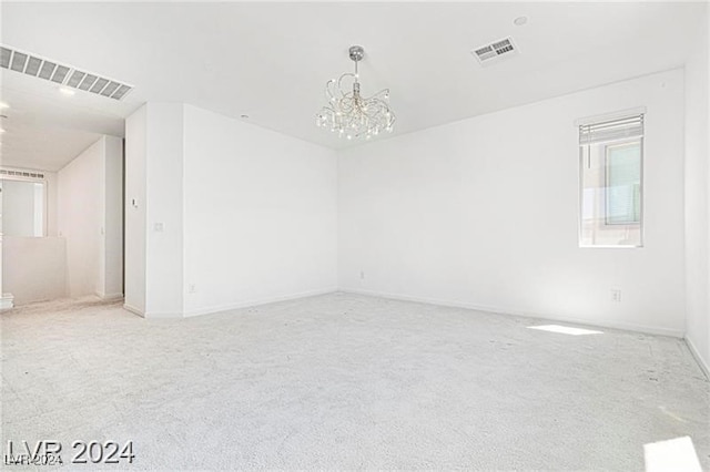 spare room with a chandelier and carpet