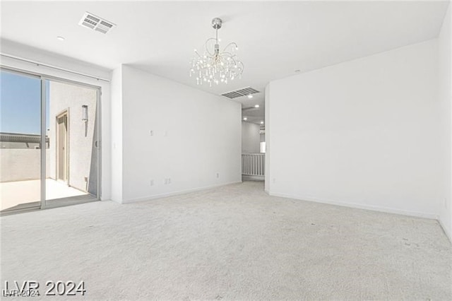 spare room featuring carpet floors and a notable chandelier