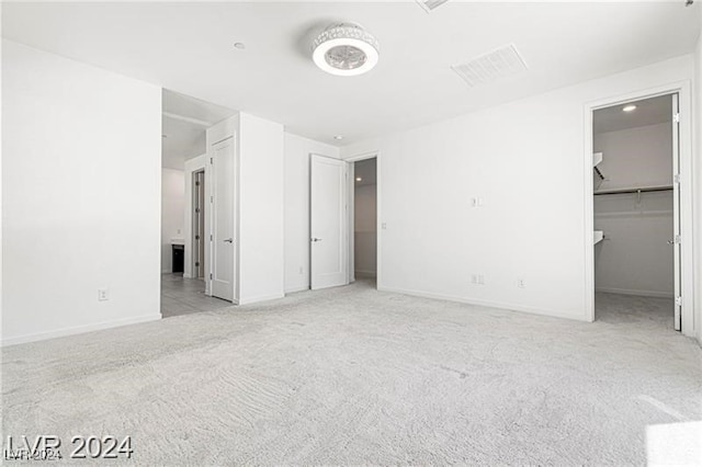 unfurnished bedroom featuring a walk in closet and light carpet