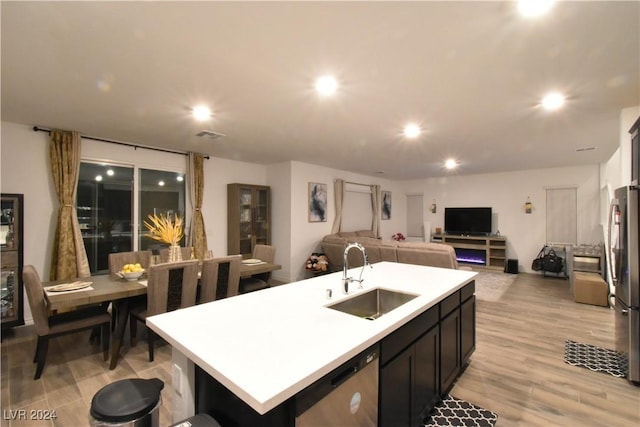 kitchen featuring appliances with stainless steel finishes, a center island with sink, light hardwood / wood-style floors, and sink