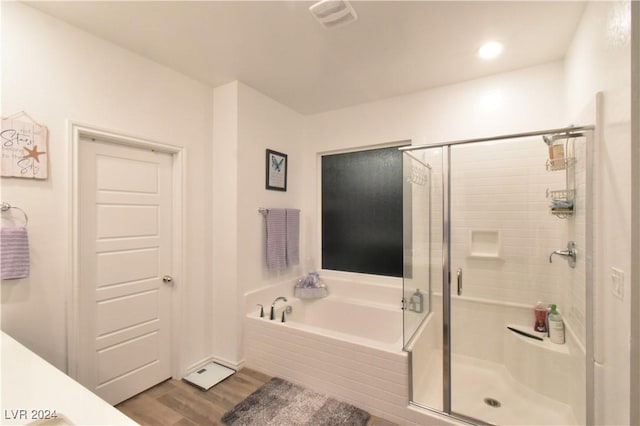 bathroom with hardwood / wood-style floors and independent shower and bath