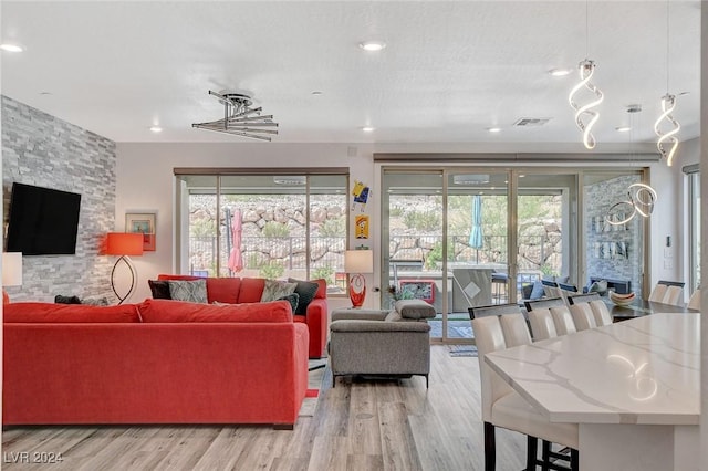 living room featuring a stone fireplace and light wood-type flooring