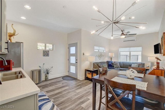 dining area with light wood-type flooring, sink, an AC wall unit, and an inviting chandelier