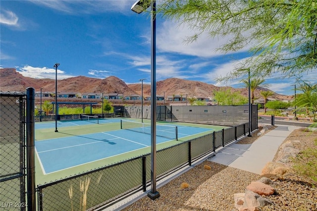 view of tennis court with basketball hoop and a mountain view