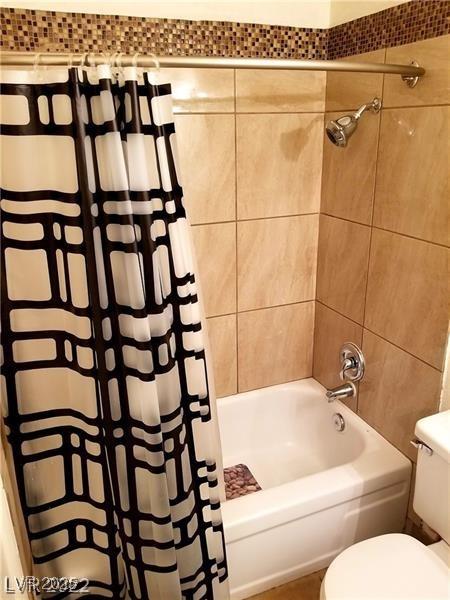 bathroom with toilet and shower / bath combo with shower curtain