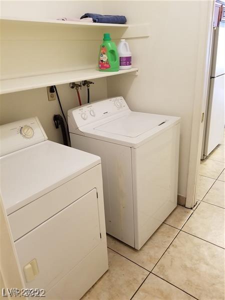 clothes washing area with light tile patterned flooring and washing machine and clothes dryer