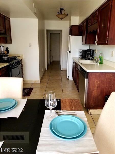 kitchen with gas stove, sink, stainless steel dishwasher, ventilation hood, and light tile patterned floors