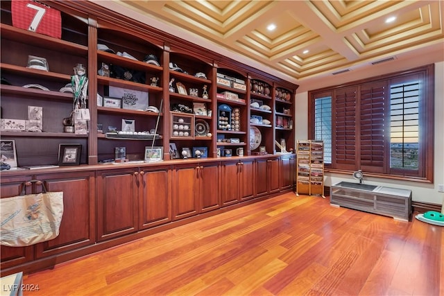 office space featuring light wood finished floors, visible vents, crown molding, and coffered ceiling