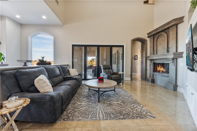 living room with a high ceiling, a tile fireplace, and light tile patterned floors