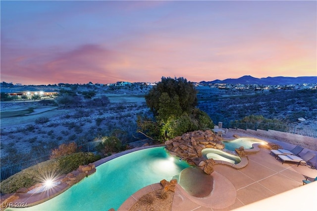 pool at dusk with a patio area and a mountain view