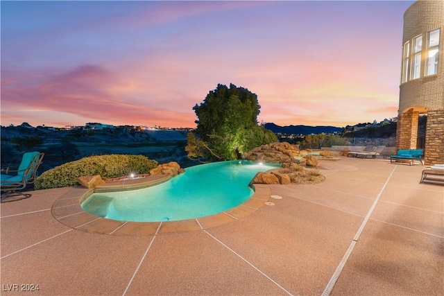 pool at dusk featuring a patio area