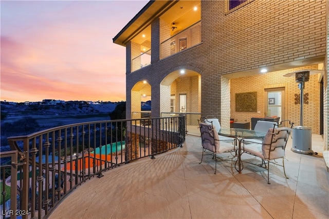 balcony at dusk featuring a patio