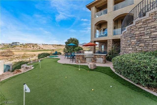 view of yard featuring a patio, exterior kitchen, and a balcony