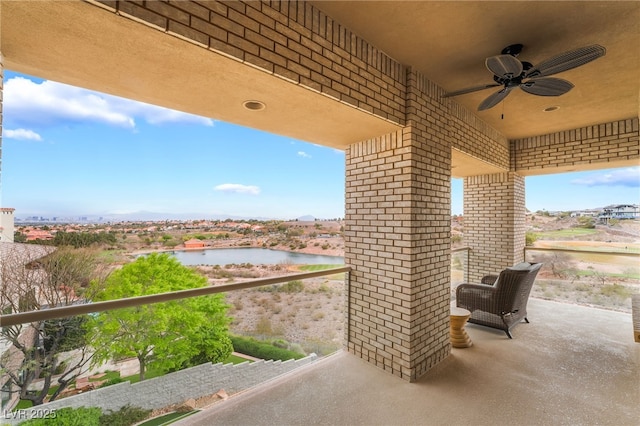 view of patio with ceiling fan, a water view, and a balcony