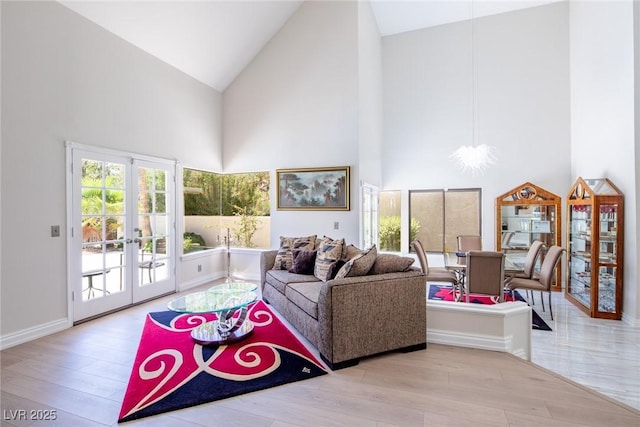 living area with high vaulted ceiling, a notable chandelier, wood finished floors, baseboards, and french doors