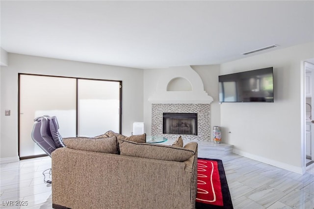 living area with a tile fireplace, visible vents, and baseboards