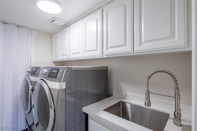 washroom with cabinet space, visible vents, washer and dryer, and a sink