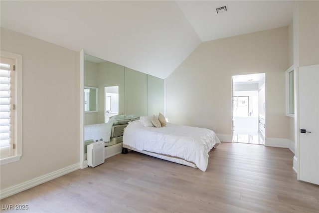 bedroom featuring light wood-type flooring, visible vents, lofted ceiling, and baseboards