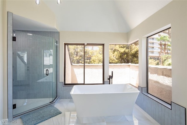 bathroom featuring lofted ceiling, a soaking tub, plenty of natural light, and a shower stall