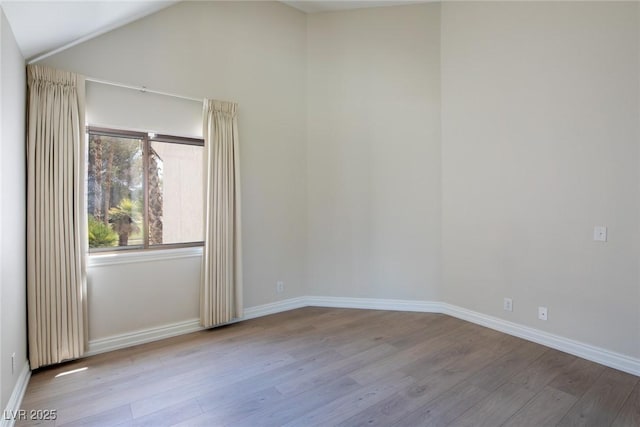 unfurnished room with baseboards, vaulted ceiling, and wood finished floors